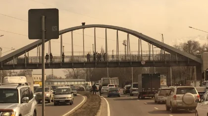 «Я на солнышке лежу»: мужчина залез на арку пешеходного моста в Алматы